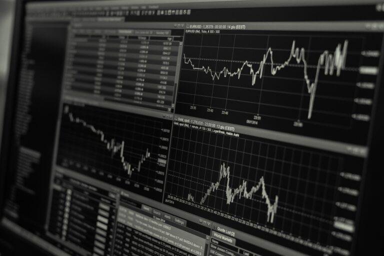Multiple monitors displaying detailed stock market charts and data